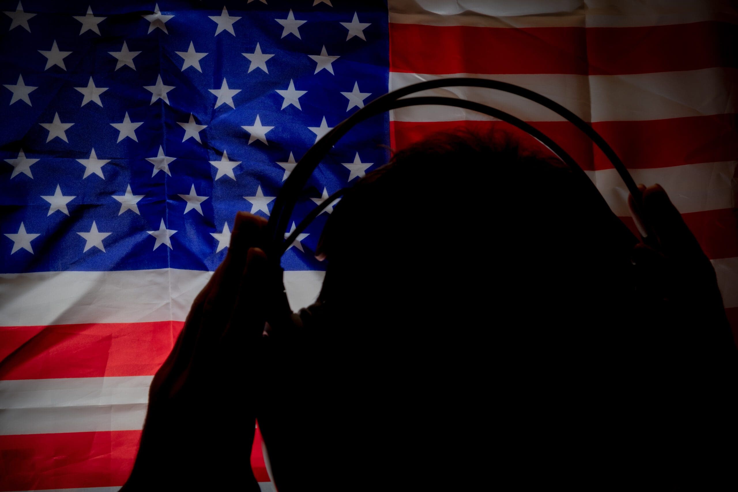 man with headphones looking at american flag